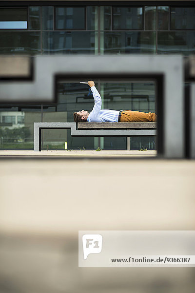 Deutschland  Hessen  Frankfurt  junger Mann auf dem Rücken liegend  Selfie mit Digital Tablet
