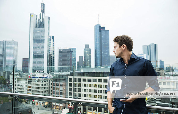 Deutschland  Hessen  Frankfurt  junger Mann mit dem Smartphone vor der Skyline