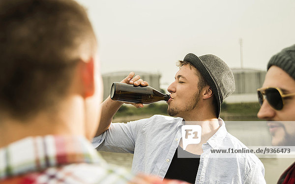 Gruppe von Freunden  die am Flussufer Bier trinken