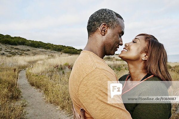 Black couple hugging on rural path