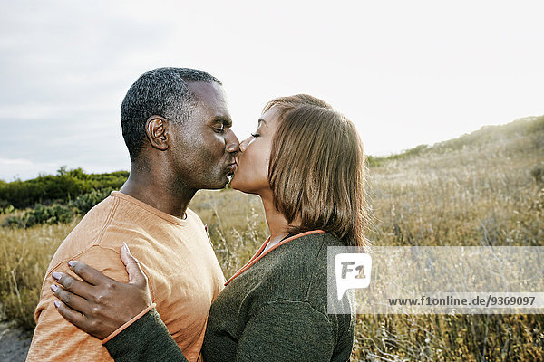 Black couple kissing on rural path