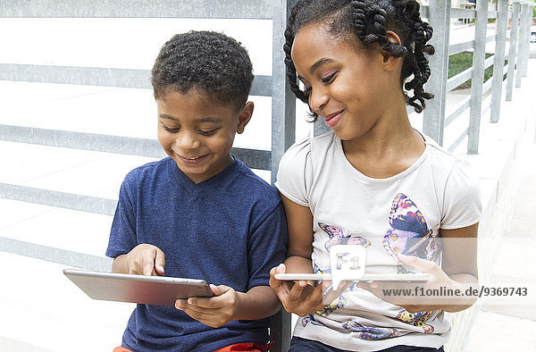 African American brother and sister using digital tablets