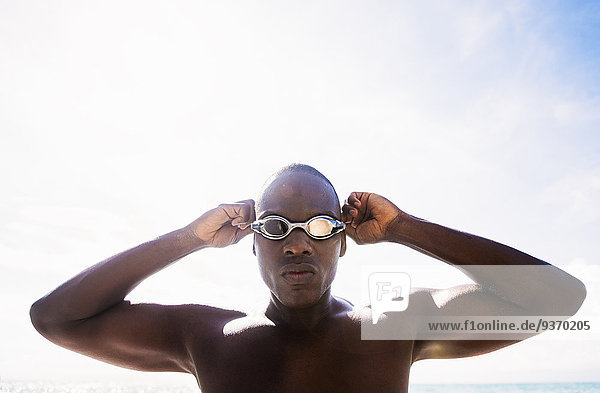Mixed race swimmer putting on goggles