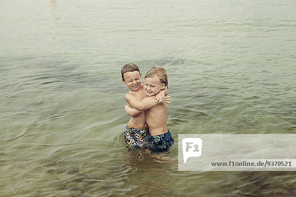 Caucasian boys hugging in lake