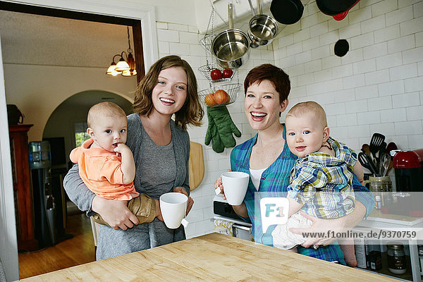 Caucasian mothers holding babies in kitchen