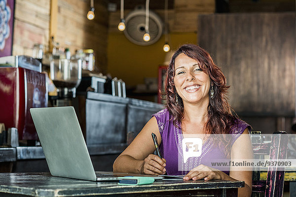 Hispanic woman using laptop in coffee shop