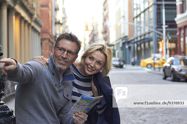 Caucasian couple holding map in city  New York City  New York  United States