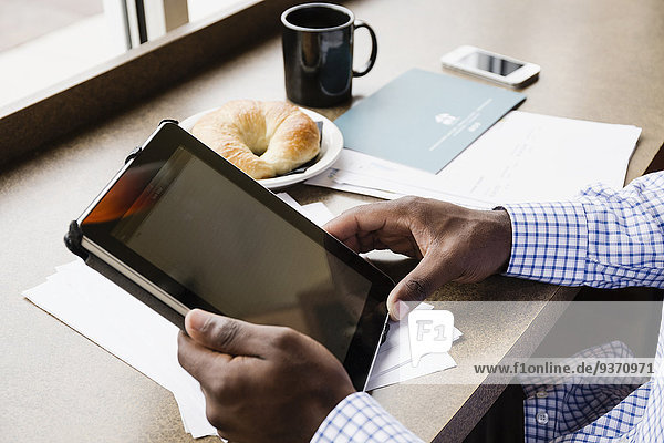 Black businessman using digital tablet in cafe