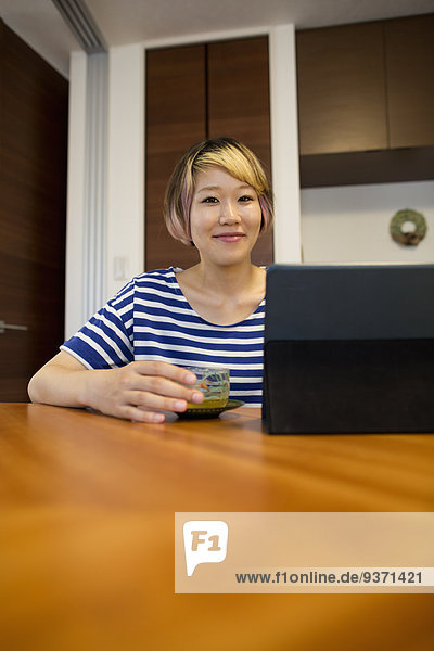 Eine Frau sitzt an einem Tisch mit einem Laptop-Computer.
