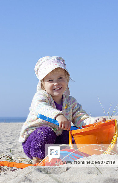 Mädchen mit Sandspielzeug am Strand