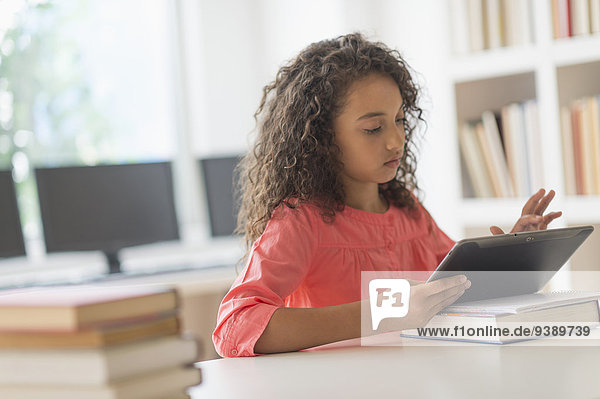 Girl (8-9) using digital tablet in classroom