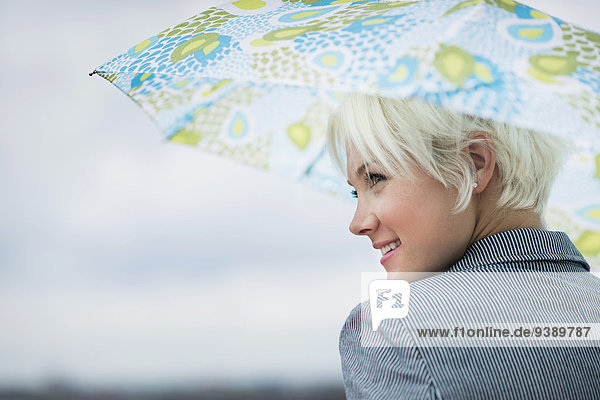 Profile of blonde woman under umbrella