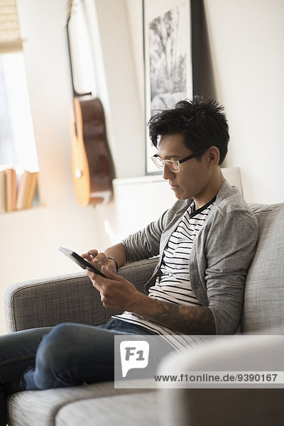 Man sitting on sofa and using tablet