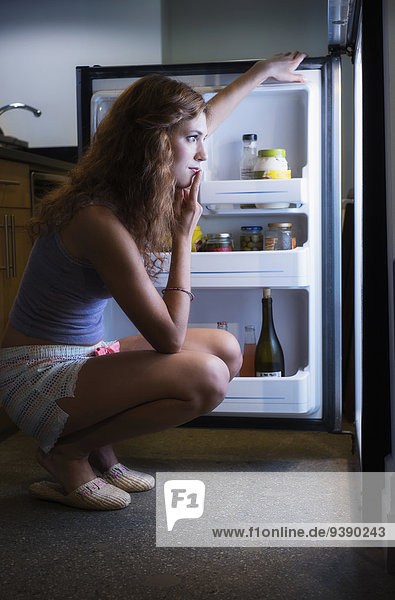 junge Frau junge Frauen sehen Kühlschrank