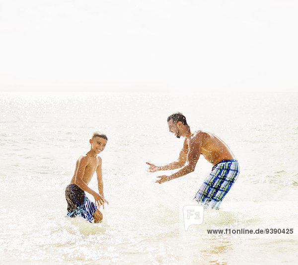 Father and son (10-11) having fun on beach