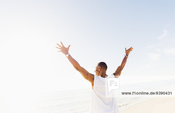 Man raising arms on beach