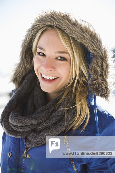 Portrait of smiling young woman in winter coat hood
