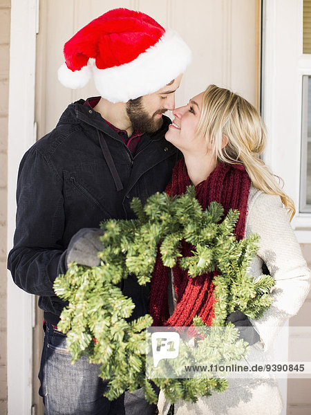 Young couple holding wreath  looking face to face