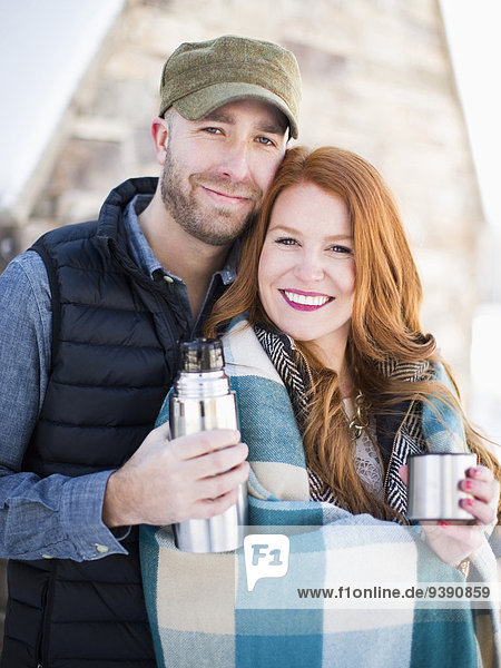 Portrait of mid adult couple having drink from vacuum flask  looking at camera