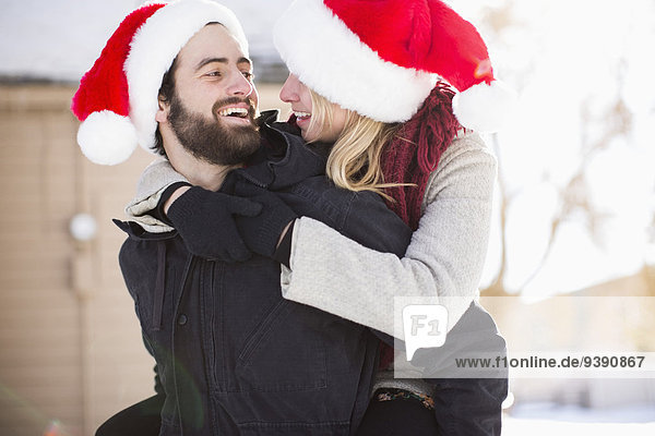 Young couple in santa hats  piggyback