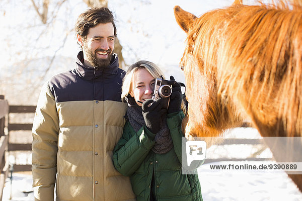 Young couple photographing horse