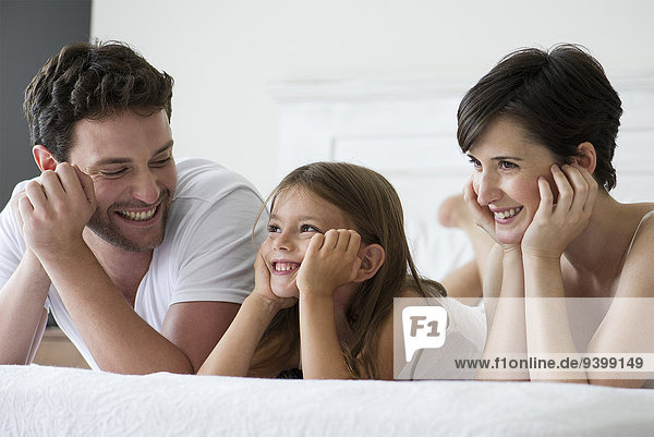 Parents and daughter lying on bed together  portrait