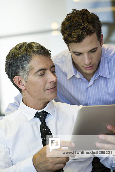 Businessmen showing assistant digital tablet