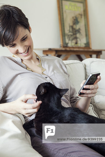 Woman sitting on sofa with cat on her lap