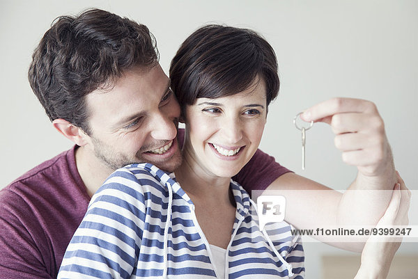 Couple looking cheerfully at house key together