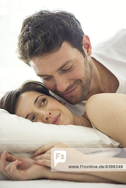 Couple together in bed  wife giving husband knowing look