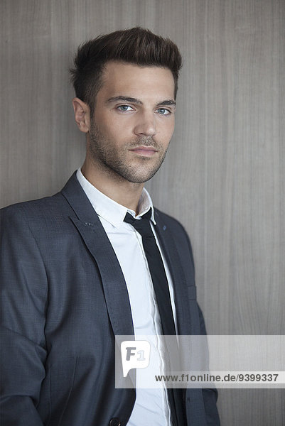 Young businessman leaning against wall  portrait