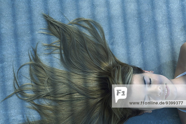 Frau im Schatten liegend mit ausgebreiteten Haaren am Boden