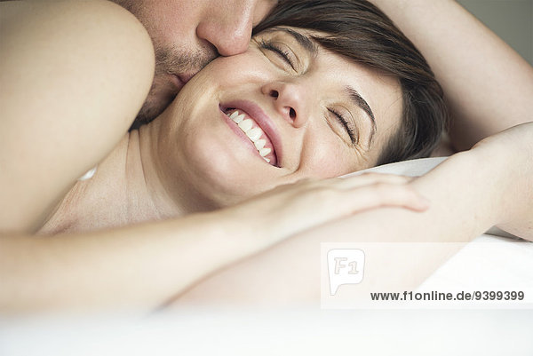 Pärchen kuscheln im Bett  Ehemann küsst Frau