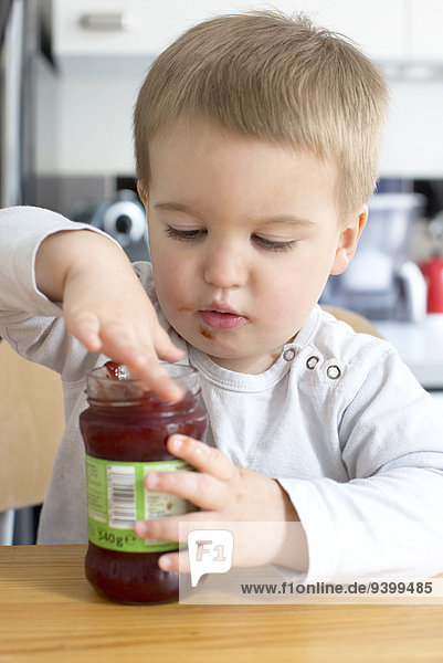 Kleinkind Junge isst Marmelade aus dem Glas mit dem Finger