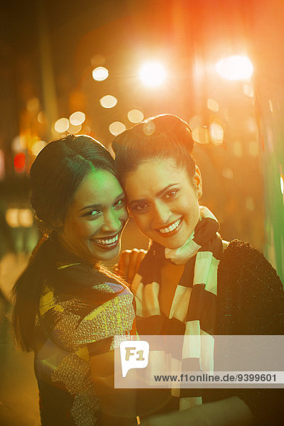 Women smiling together on city street at night