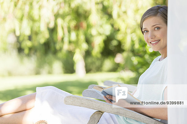 Frau liest Buch im Gartenstuhl im Freien