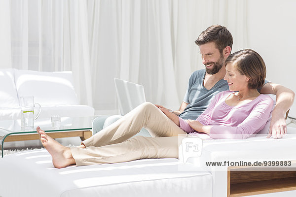 Couple using laptop on sofa in modern living room