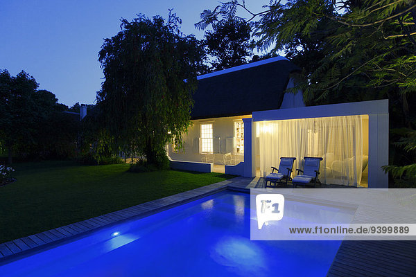 Modernes Haus mit Blick auf das beleuchtete Schwimmbad bei Nacht