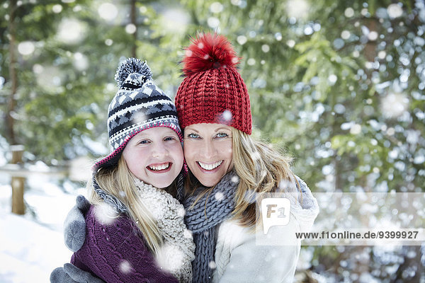 Mother and daughter hugging in snow