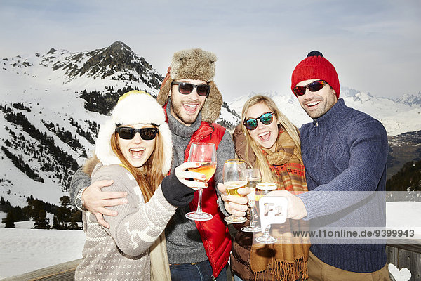 Paare feiern mit Getränken im Schnee
