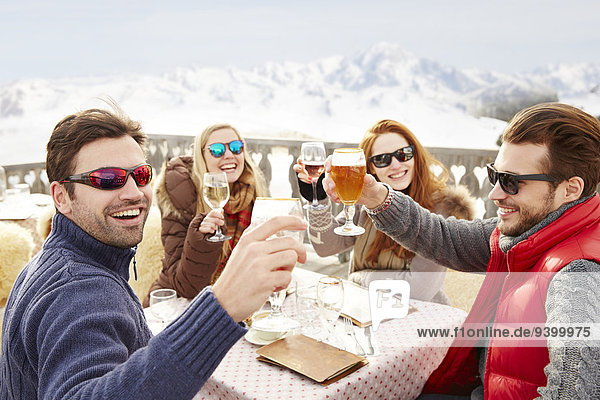 Freunde beim Feiern mit Getränken im Schnee
