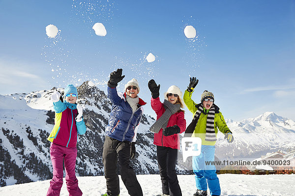 Family throwing snowballs on mountain top