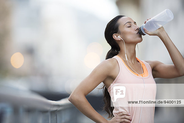 Frau trinkt Wasser nach dem Training auf der Stadtstraße