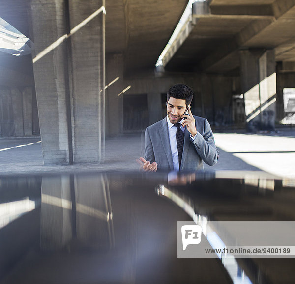 Businessman talking on cell phone in parking garage