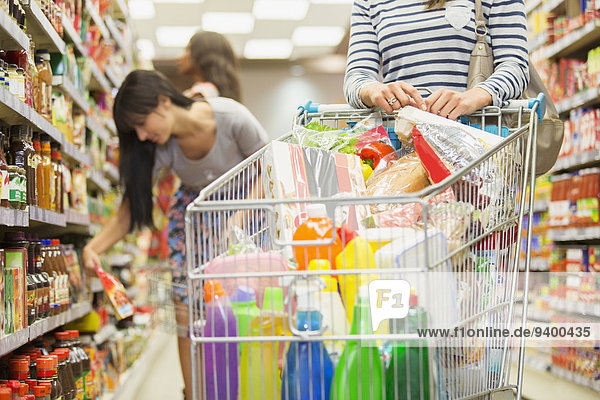 Frau schiebt vollen Einkaufswagen im Lebensmittelladen