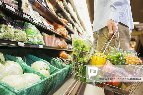 Mann mit vollem Einkaufskorb im Lebensmittelgeschäft