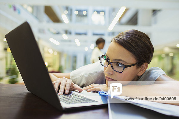 Geschäftsfrau entspannt mit Laptop im Bürogebäude