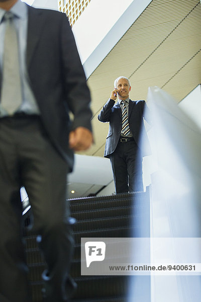 Geschäftsmann im Gespräch auf dem Handy auf der Rolltreppe im Büro