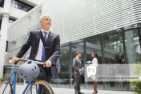 Geschäftsmann mit dem Fahrrad vor dem Bürogebäude