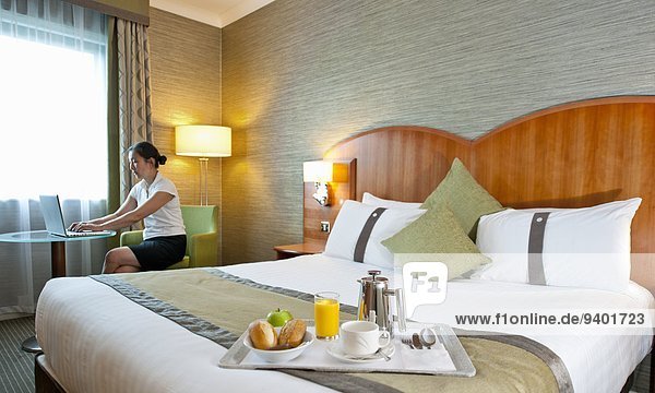 Frau Notebook Zimmer arbeiten Bett Hotel Hintergrund Seitenansicht Frühstück Business